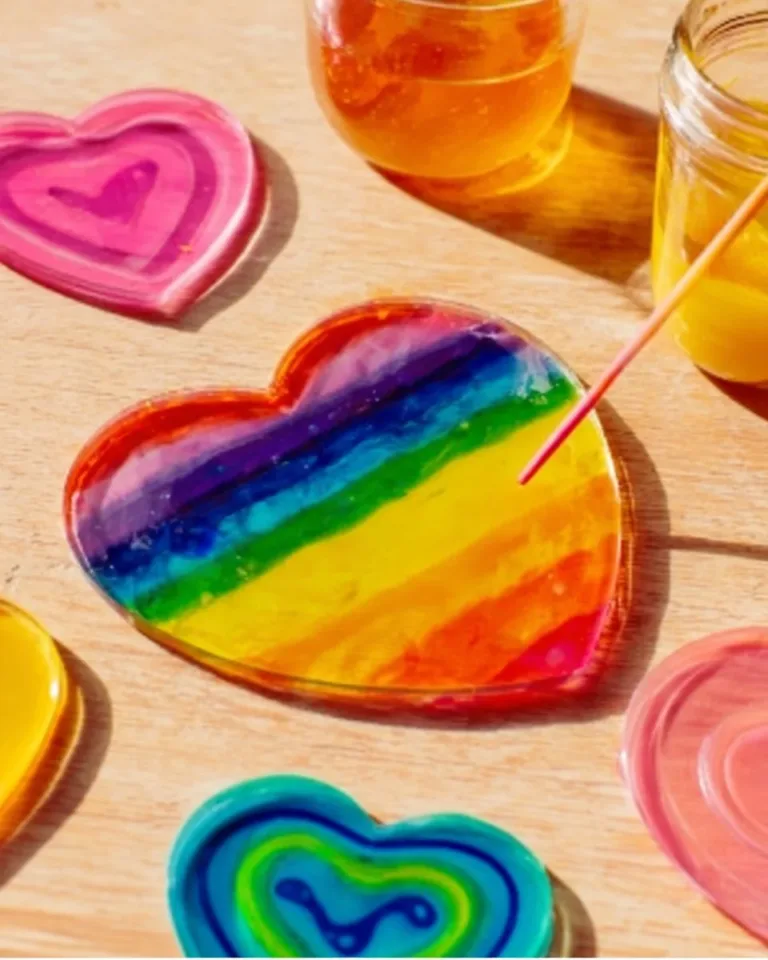 Colorful homemade rainbow glue suncatchers hanging in a window